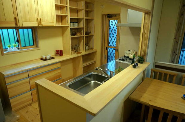 対面キッチンのカウンターは無垢の赤松材で　食器棚はオリジナルの赤松の食器棚と造作棚